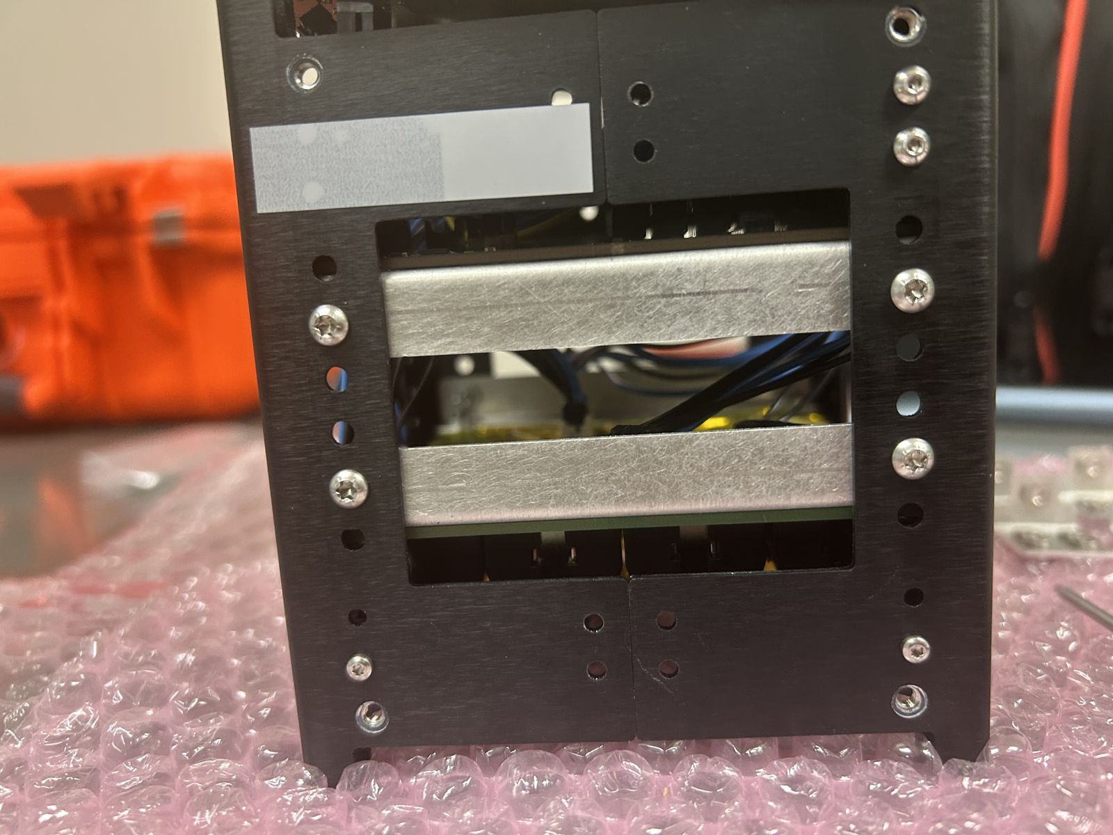 Side of the CubeSat frame showing two metal brackets and mounting screws