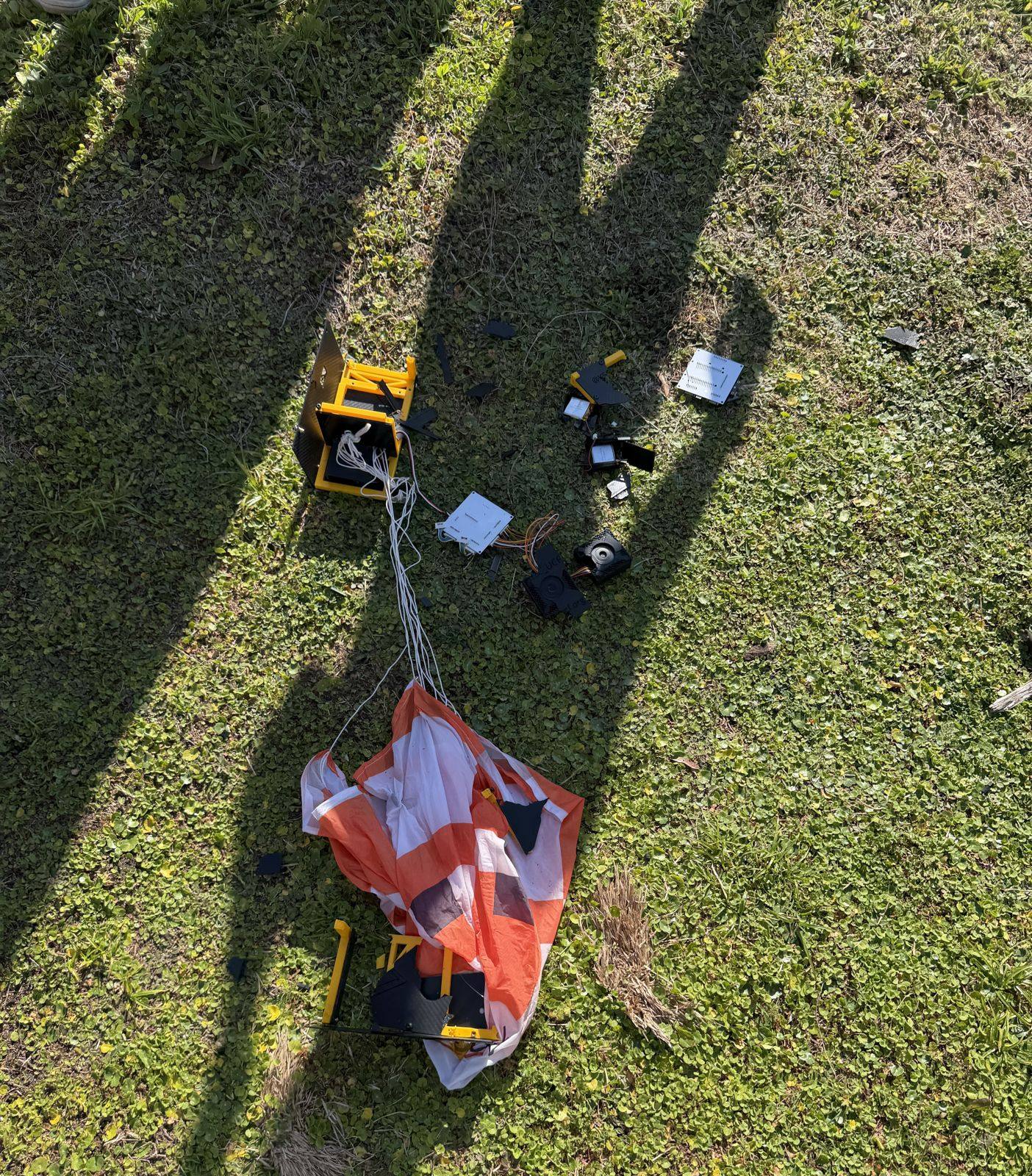 Damaged payload and tangled parachute on the grass after landing
